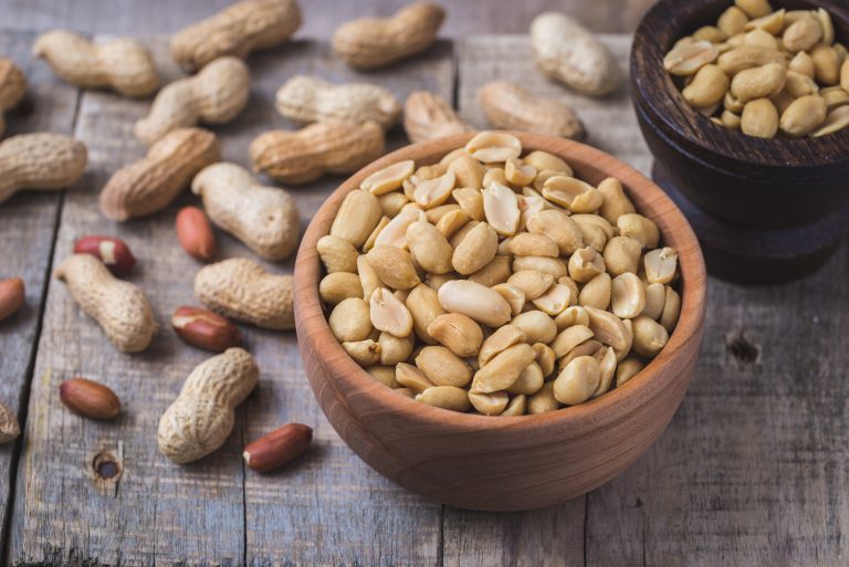 Peanuts in small wooden bowl on natural rustic desk